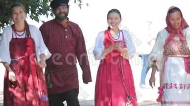 一群穿着俄罗斯民族服饰在大自然中行走的男女。 微笑。 庆祝活动